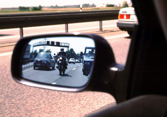 Spiegelnde Straße im Rückspiegel. Blick vom Auto Seitenspiegel